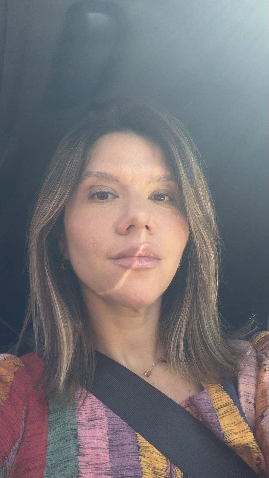 Carla olhando para a câmera, com luz do sol no rosto